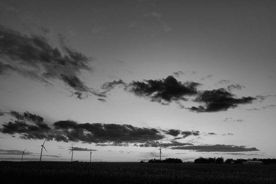 wind mills in vast field at sunset with clouds in the sky